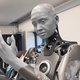 Ameca ponders which cruel god would make her while another robot mimics our reaction to her existence in the corner.